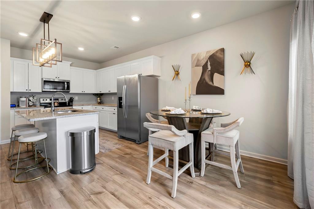 7098 Chara Lane Atlanta, GA 30331 - Photo 11 of 25 a kitchen with kitchen island granite countertop a table chairs refrigerator and microwave