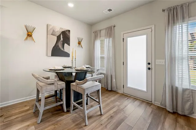 a kitchen with kitchen island granite countertop a table chairs refrigerator and microwave