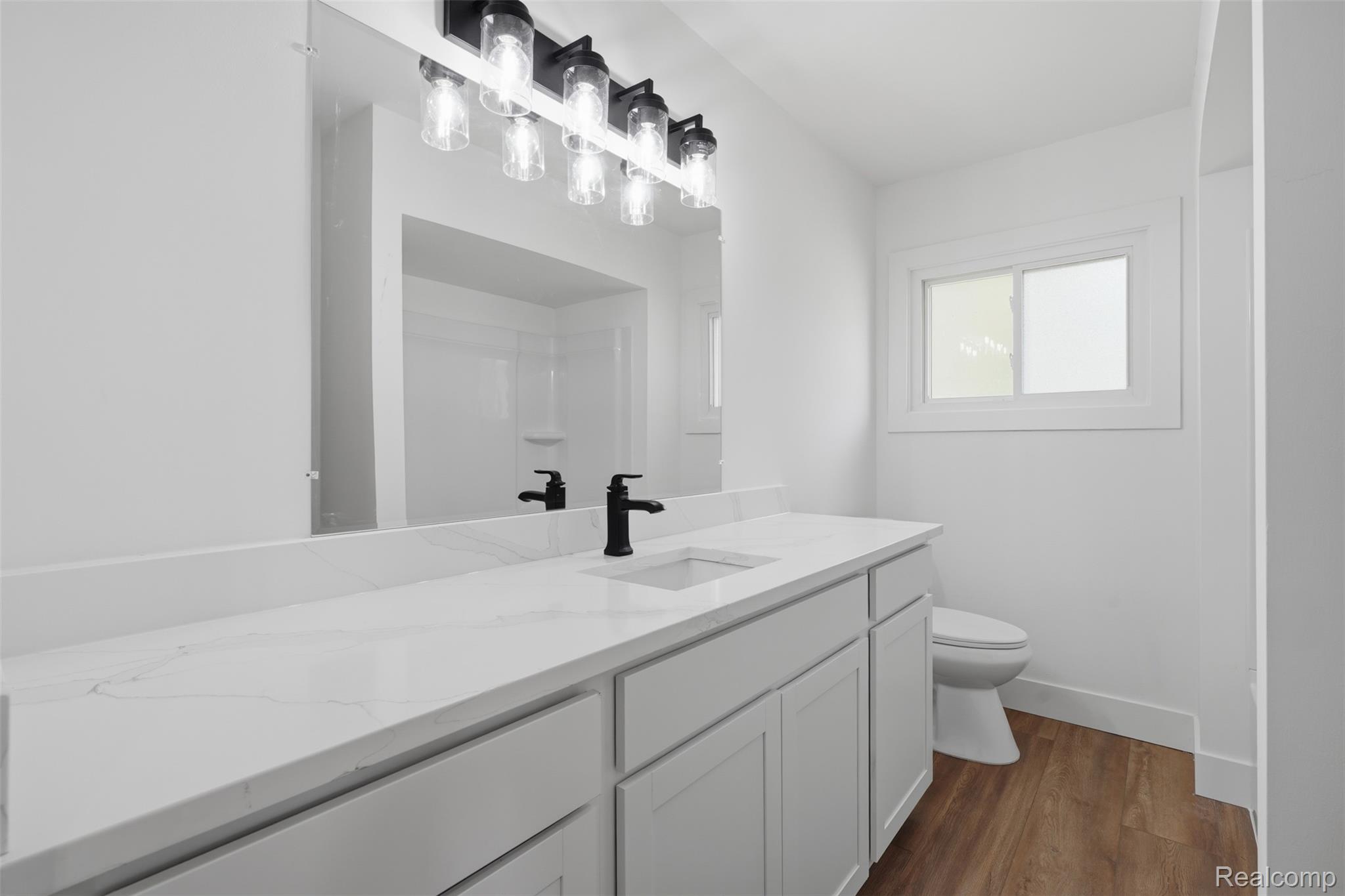 4655 Denton Road Canton, MI 48188 - Photo 30 of 54 White vanity with a single basin, white countertop, and dark-finish faucet, complemented by a large wall-mounted mirror and dark-finish light fixture