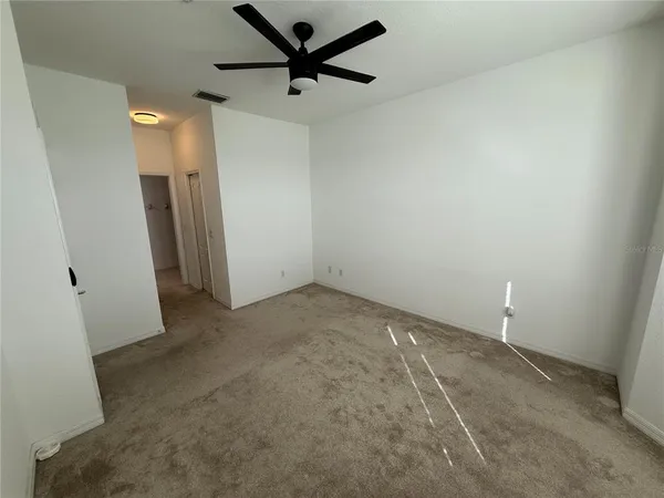 an empty room with closet and a ceiling fan