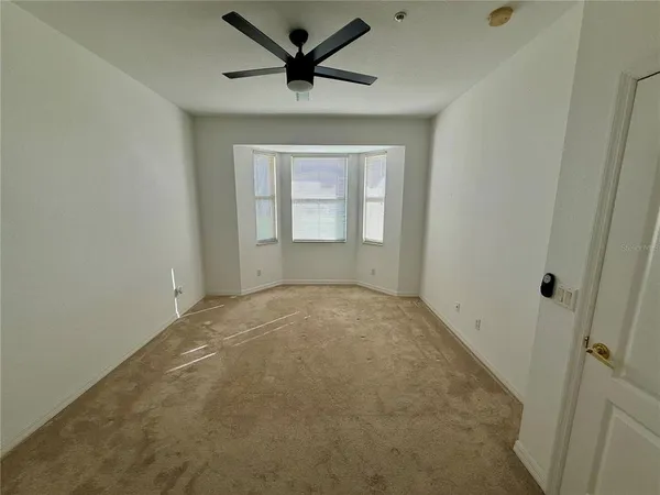 an empty room with a ceiling fan and window