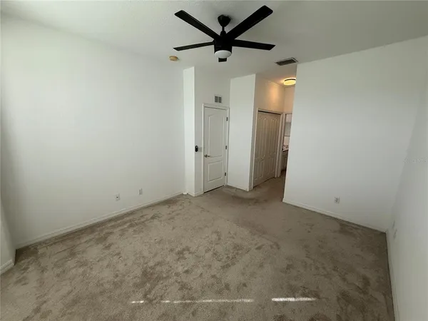 en empty room with a ceiling fan and a window