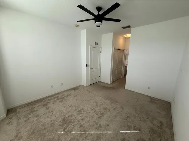 en empty room with a ceiling fan and a window