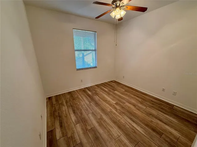 an empty room with chandelier fan and windows