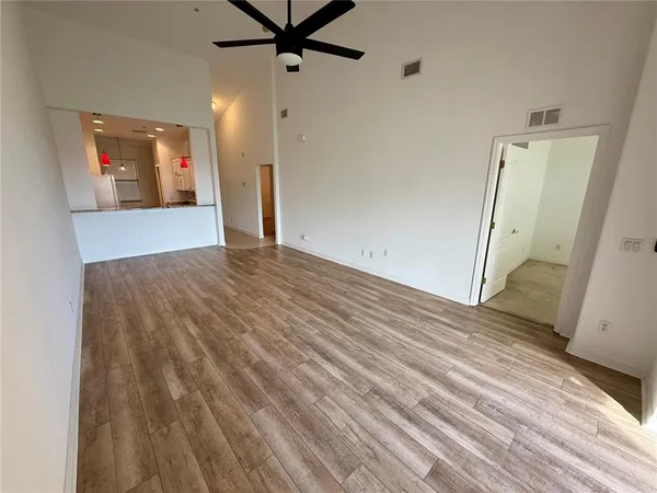an empty room with wooden floor and a ceiling fan