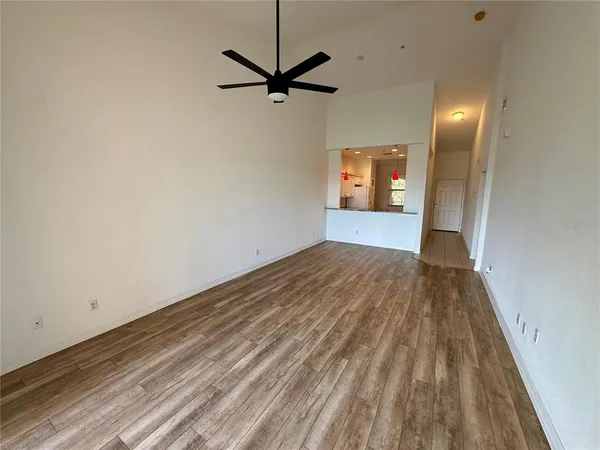 a view of a room with a ceiling fan and wooden floor