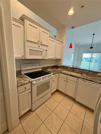 a white kitchen with granite top and stainless steel appliances