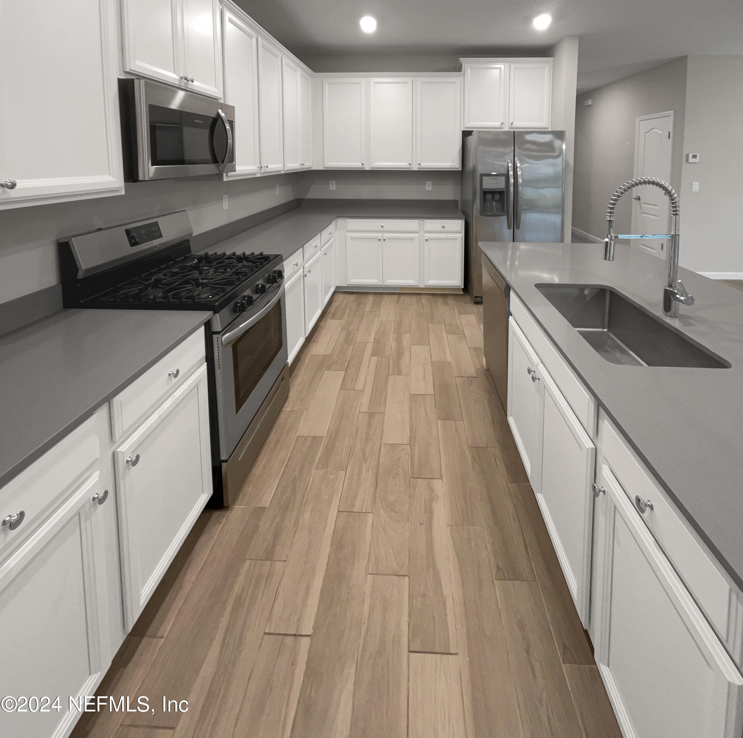 188 Bloomfield Way St. Augustine, FL 32092 - Photo 15 of 18 a large kitchen with stainless steel appliances granite countertop a stove a sink dishwasher and a microwave oven with wooden floor