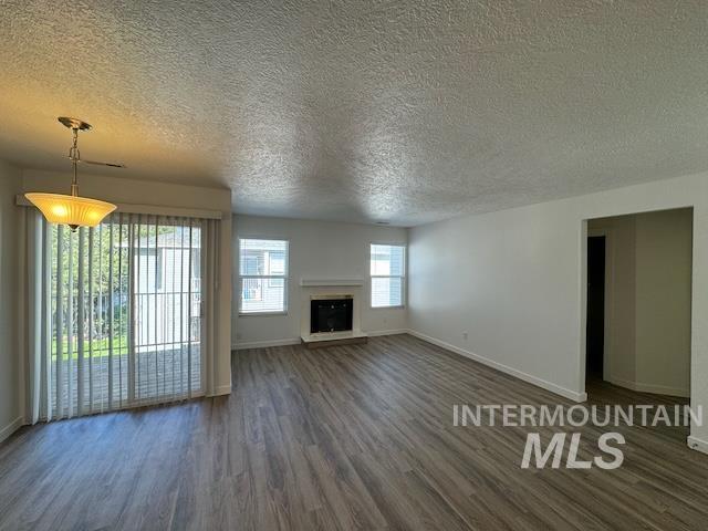 9086 West Sigmont Lane, Unit 202 Boise, ID 83709 - Photo 1 of 6 Unfurnished living room featuring a textured ceiling, dark wood-style flooring, and a fireplace with raised hearth