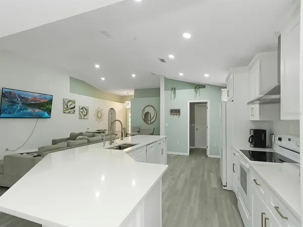 a large white kitchen with stainless steel appliances a lot of counter space and a sink