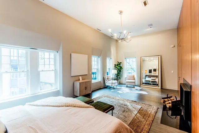 a spacious bedroom with a bed a chandelier and large window
