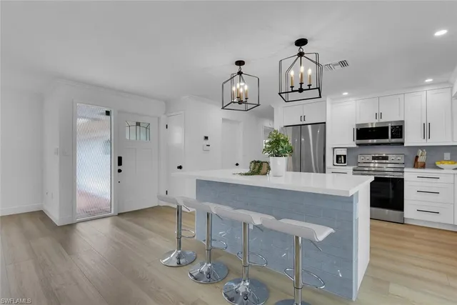 a kitchen with stainless steel appliances granite countertop a kitchen island hardwood floor and a sink