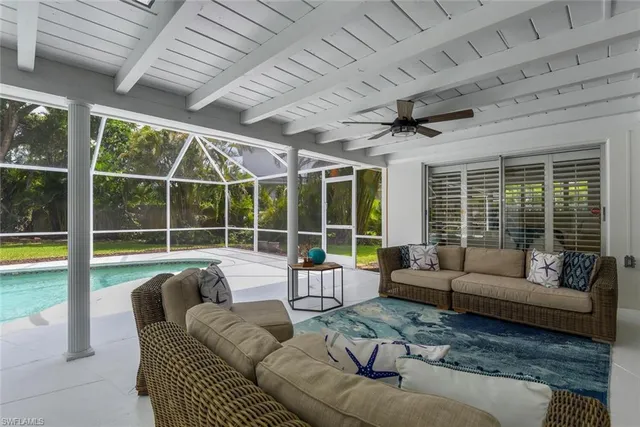 a view of a swimming pool with wooden chairs and floor to ceiling window