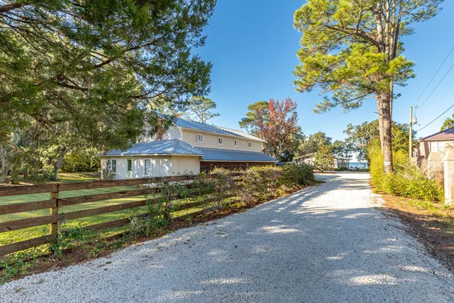 a view of a house with a big yard plants and large trees