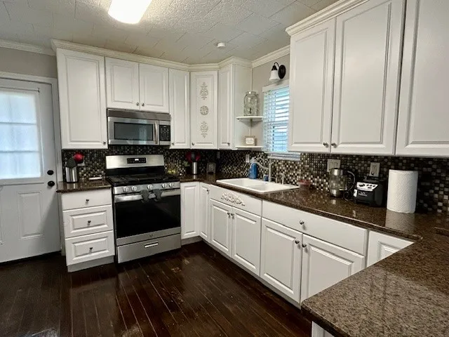 a kitchen with stainless steel appliances granite countertop a stove a sink and white cabinets