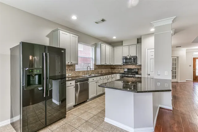 a kitchen with stainless steel appliances granite countertop a refrigerator and a stove top oven