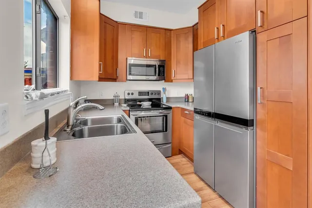 a kitchen with stainless steel appliances a refrigerator a sink a stove and cabinets