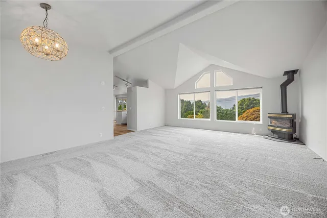 a view of an empty room with a window and kitchen view