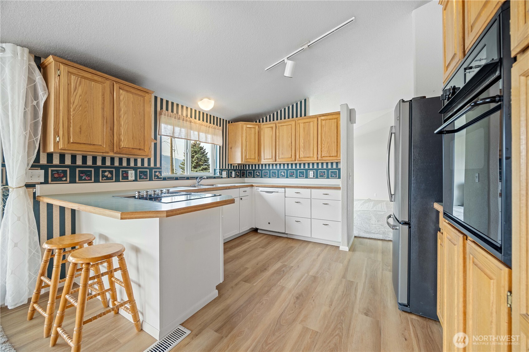 744 Wapato Lake Road Manson, WA 98831 - Photo 23 of 40 a large kitchen with stainless steel appliances granite countertop a refrigerator a sink dishwasher a stove and white countertops with wooden floor