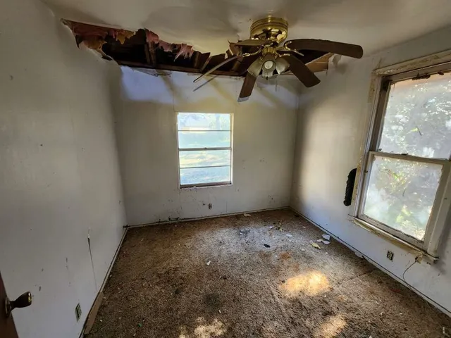 en empty room with windows and ceiling fan