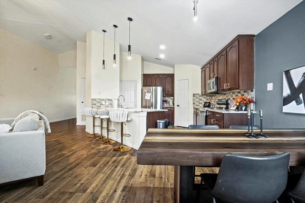 1412 Cheyenne Road Wylie, TX 75098 - Photo 13 of 24 Kitchen featuring tasteful backsplash, a breakfast bar, lofted ceiling, appliances with stainless steel finishes, and pendant lighting