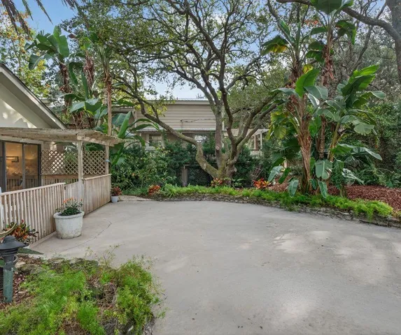 a view of a house with potted plants and large trees