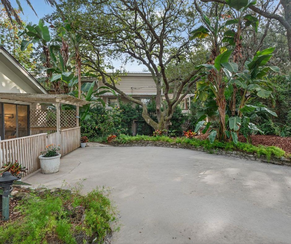 a view of a house with potted plants and large trees