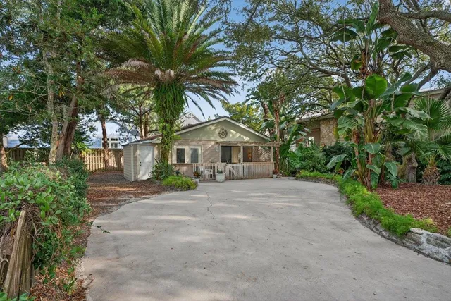 a view of a house with potted plants and large trees