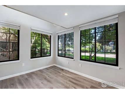 a view of an empty room with wooden floor and windows