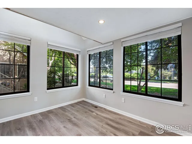 a view of an empty room with wooden floor and windows