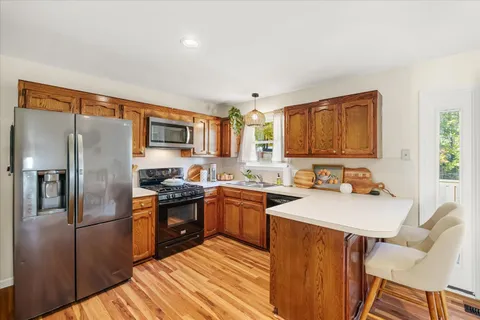 a kitchen with stainless steel appliances granite countertop a refrigerator a stove top oven a sink dishwasher and white cabinets with wooden floor