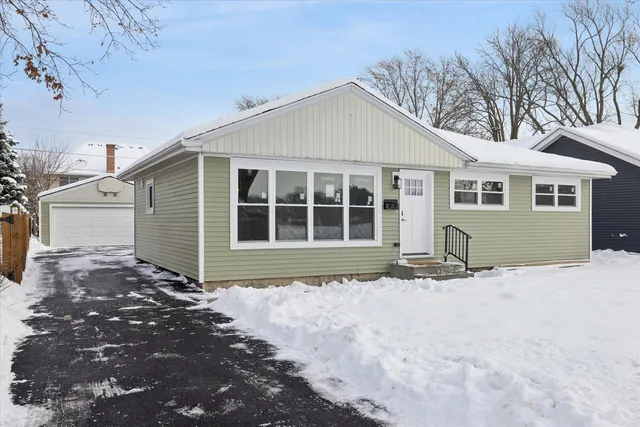 a front view of a house with a yard covered in snow