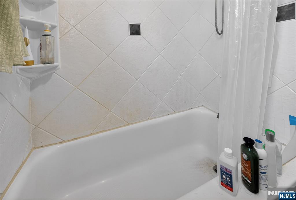 243 Johnson Avenue, Unit L4 Hackensack, NJ 07601 - Photo 19 of 25 a bathroom with a white bath tub and a shower curtain