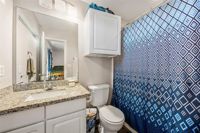 a bathroom with a granite countertop toilet sink and mirror