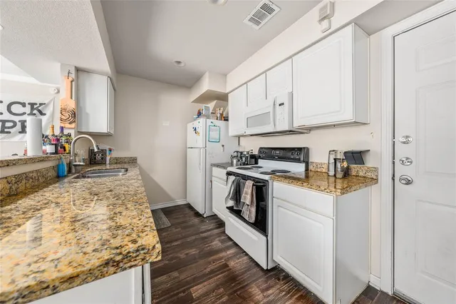 a kitchen with granite countertop a sink stove and refrigerator