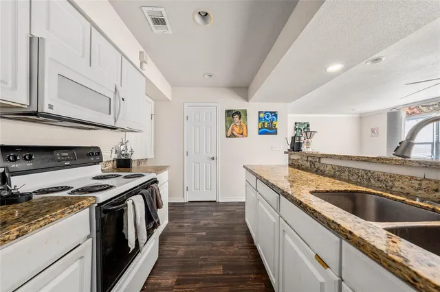 a kitchen with granite countertop a sink and a stove top oven