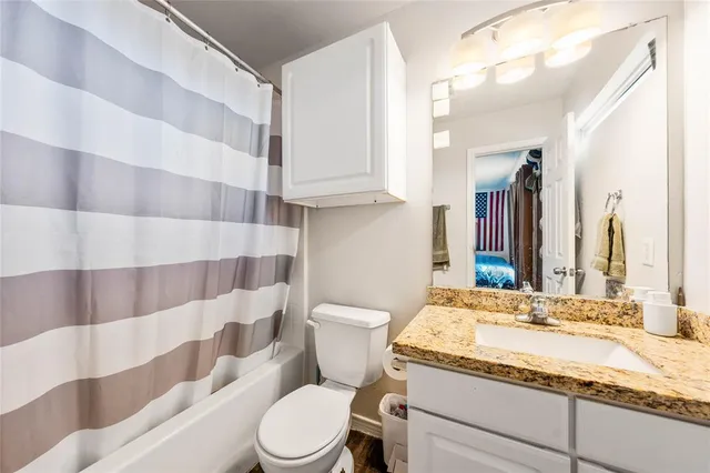 a bathroom with a granite countertop bathtub sink vanity mirror and toilet