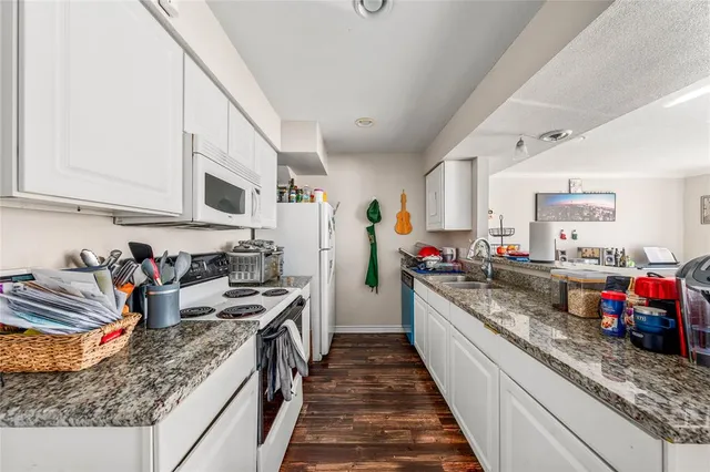 a kitchen with kitchen island granite countertop lots of counter top space a sink and appliances