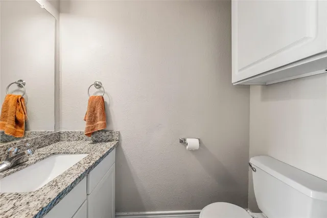 a bathroom with a granite countertop sink and a toilet