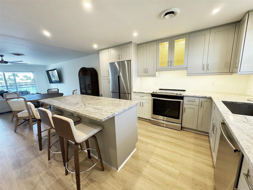 2330 Northeast 36th Street, Unit 11 Lighthouse Point, FL 33064 - Photo 1 of 11 a kitchen with stainless steel appliances granite countertop a kitchen island a stove a sink a dining table and chairs