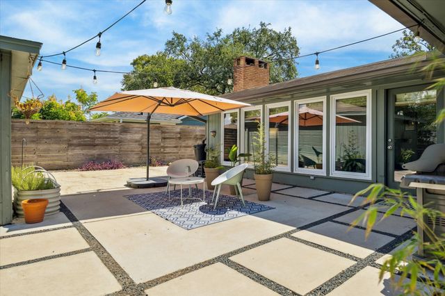 a view of a patio with table and chairs potted plants and a palm tree