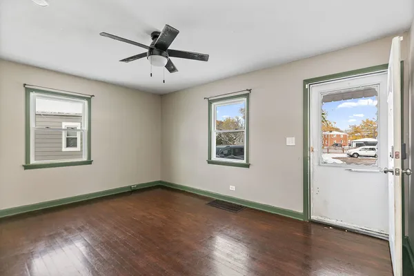an empty room with wooden floor a ceiling fan and windows