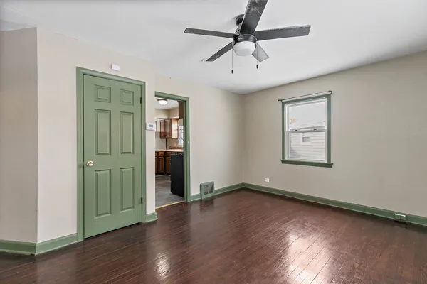 an empty room with wooden floor a ceiling fan and windows