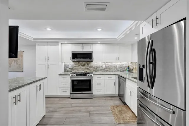 a kitchen with stainless steel appliances white cabinets a sink and a stove