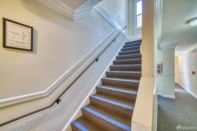 a view of staircase with lots of frames on wall and a window