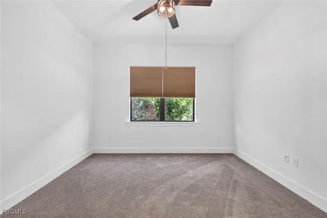 an empty room with a window and a ceiling fan