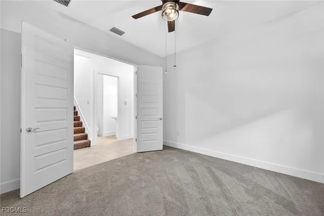an empty room with a ceiling fan and carpet