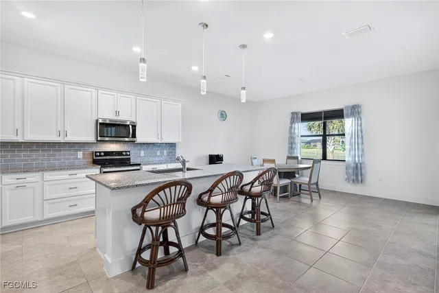 a kitchen with stainless steel appliances granite countertop table chairs sink and cabinets
