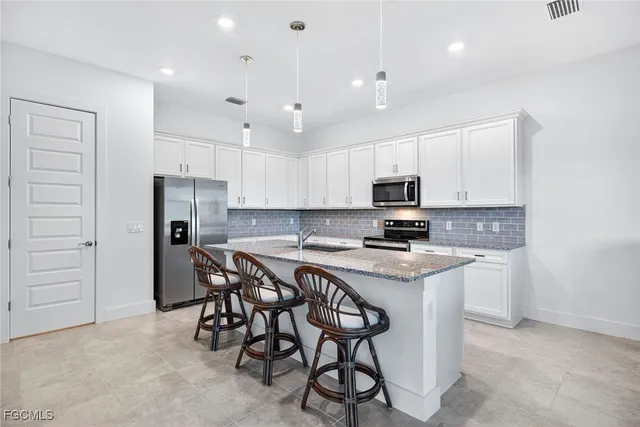 a kitchen with stainless steel appliances granite countertop a stove a sink a refrigerator and a microwave