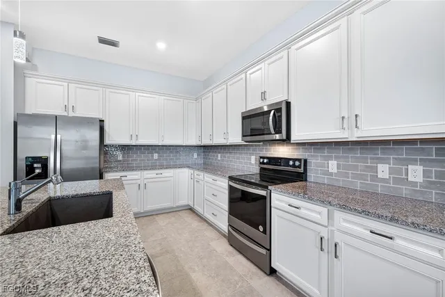 a kitchen with granite countertop a refrigerator stove and microwave